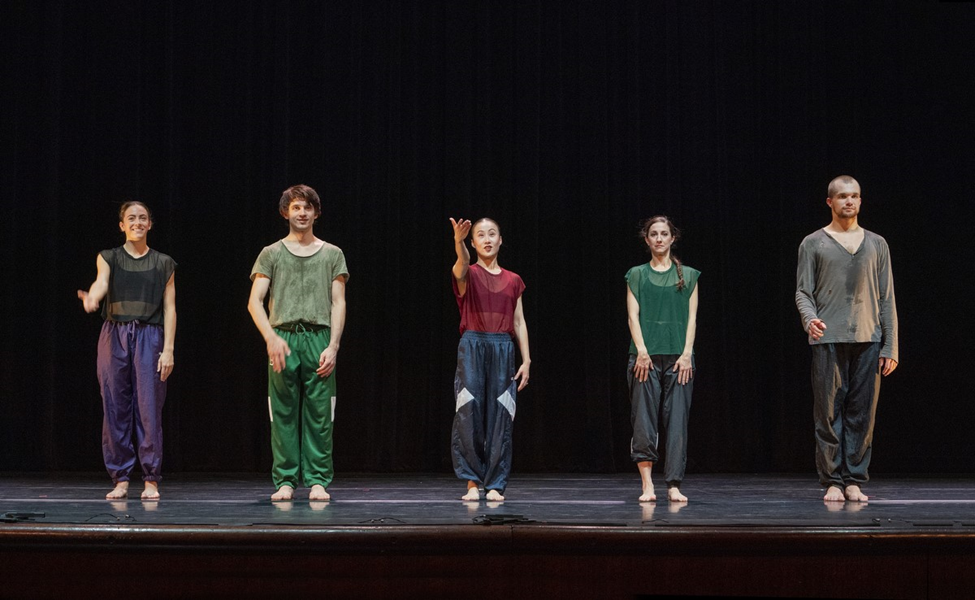 the five artists in sweat pants of different colors and loose shirts, smile and look relieved and sweaty as they take their bows on stage